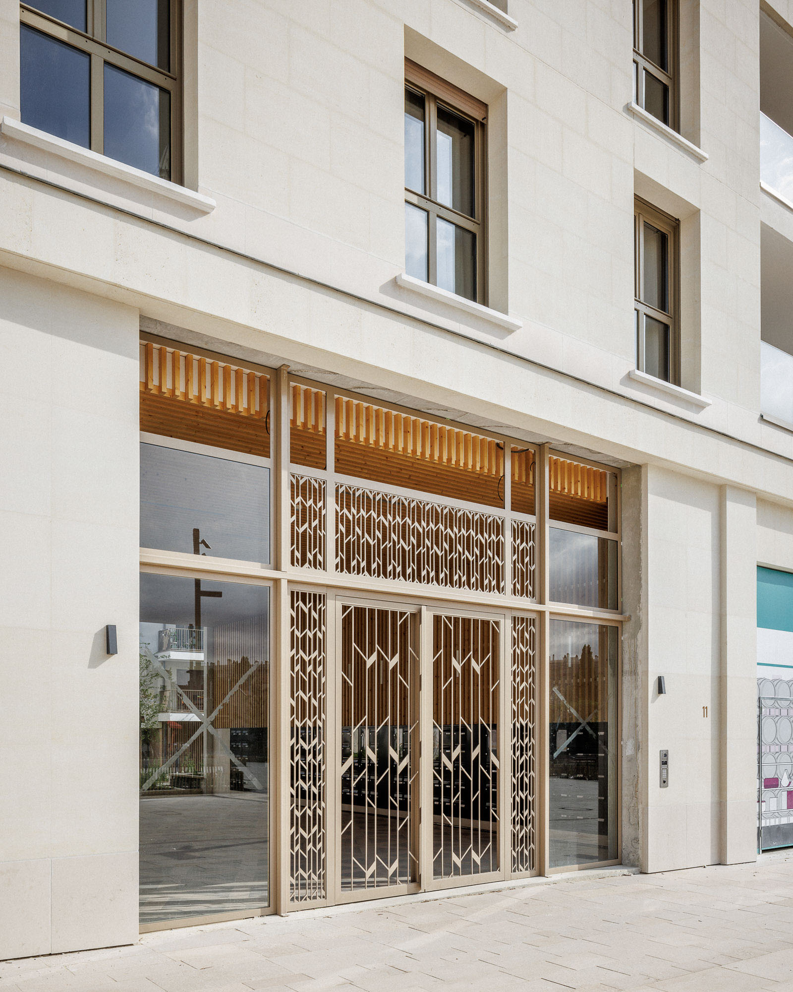Détails des serrureries thermo laquées bruns et bardage bois de la porte vitrée du hall d'entrée de l'immeuble de logements ZAC Jean ZAY à Antony par Cussac Architectes et Associés (ca+a)